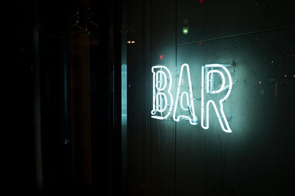Enseigne néon "BAR" blanche lumineuse sur fond sombre, style rétro vintage
