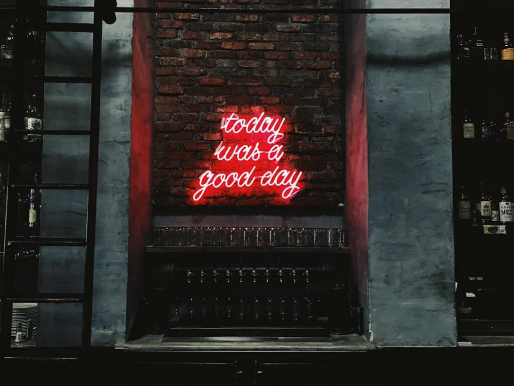 Néon citation rouge script "today was a good day" au-dessus du comptoir d'un bar