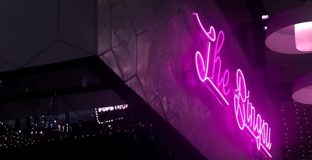 Logo en néon LED rose cursif personnalisé sur facade sombre, illustration de reproduction de logo complexe