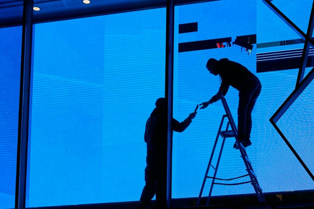 Techniciens posant une enseigne lumineuse en façade, illustrant le process de mise en service sur site