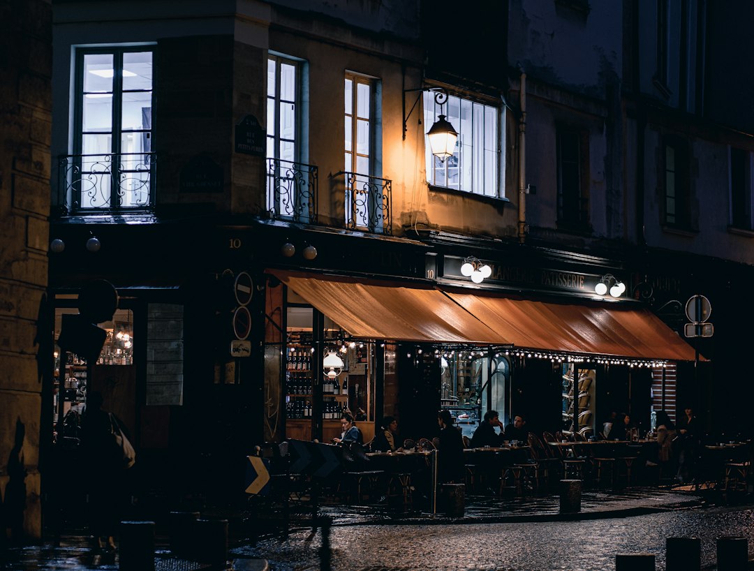 Bistro parisien la nuit avec terrasse et devanture lumineuse sur rue pavée, illustration de la visibilité des enseignes pour les piétons