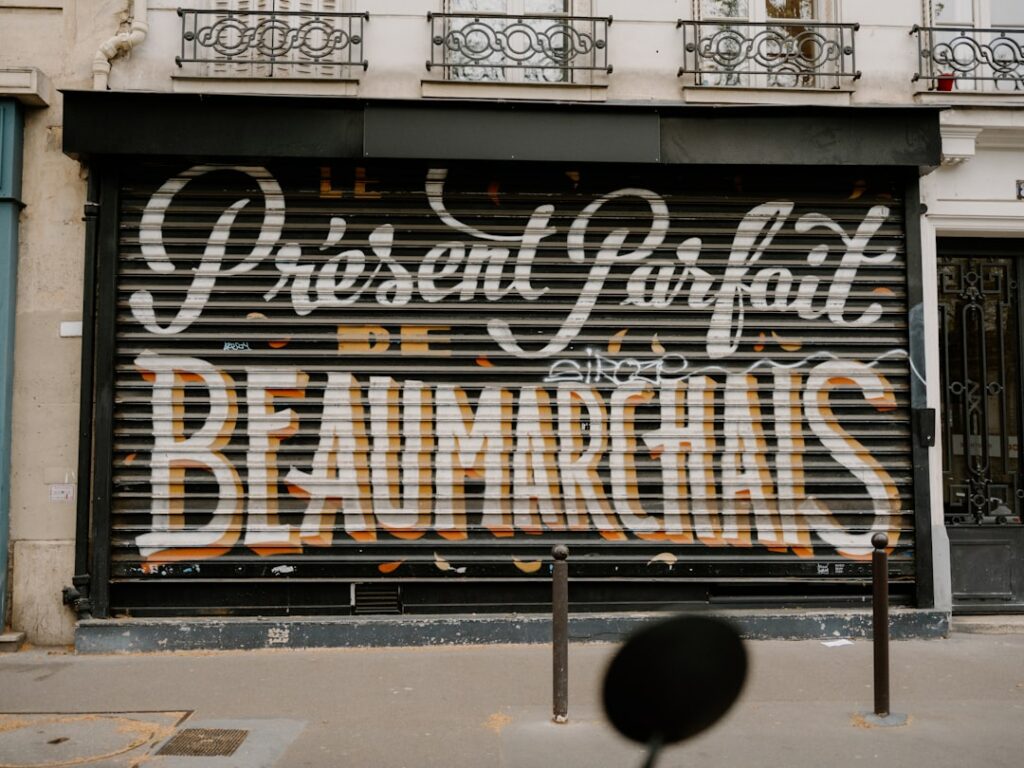 Devanture commerciale parisienne avec rideau métallique décoré dans un immeuble haussmannien, illustrant les contraintes d'affichage en zone réglementée à Paris