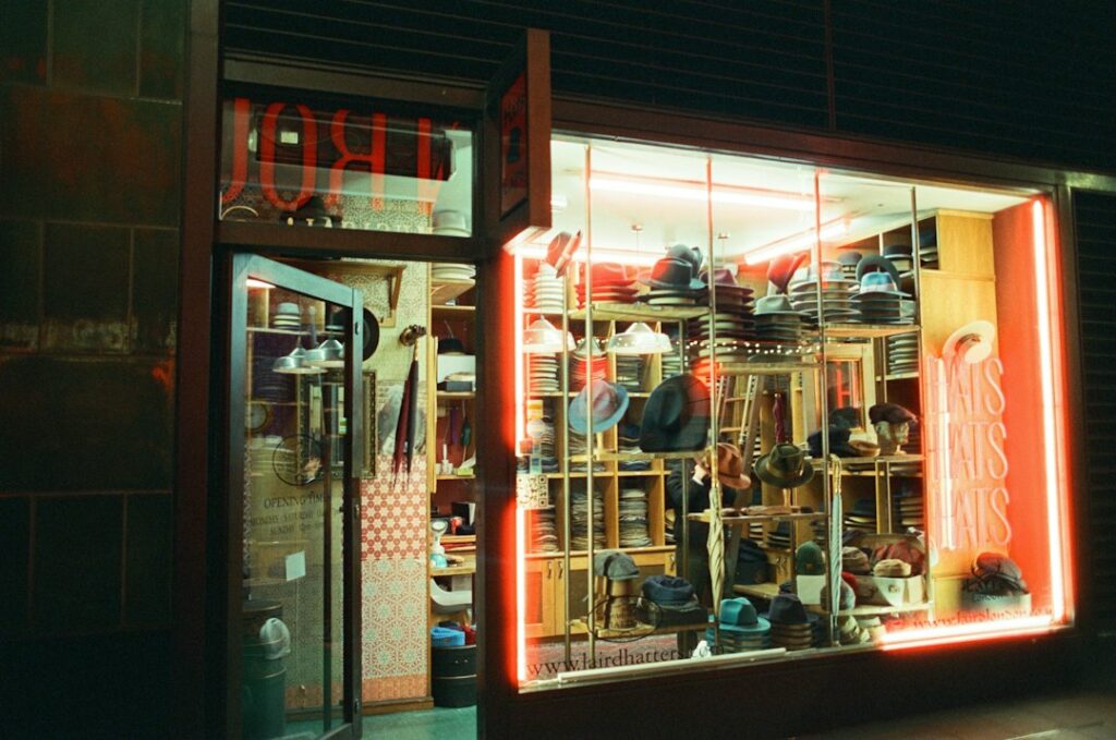Vitrine de boutique illuminée par néon rouge la nuit, avec enseignes lumineuses attirant le flux piéton