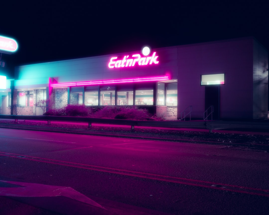 Enseigne lumineuse néon rose illuminant la façade d'un restaurant la nuit — exemple d'enseigne extérieure pour restaurateurs